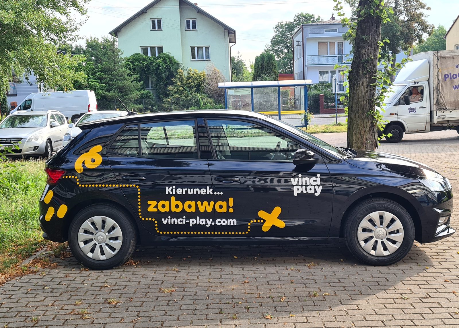 Czarny samochód osobowy oklejony kolorową grafiką reklamową