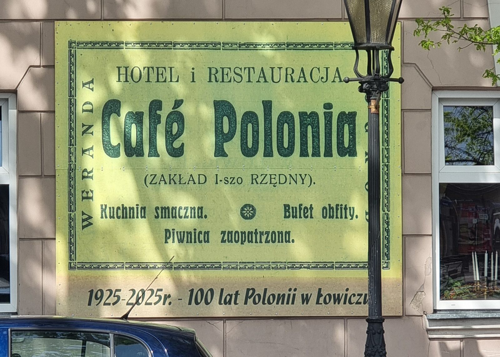 Szyld kawiarni na wysięgniku przy kamienicy